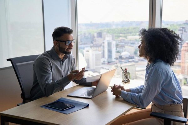 HR consultant meeting a client in a high-rise Dubai office with city skyline view